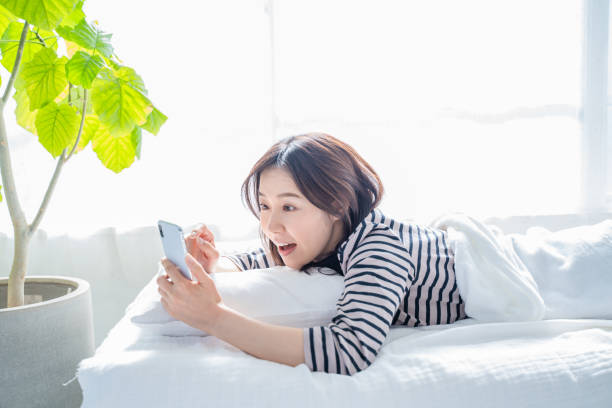 istock Smiling woman looking at smartphone screen in bed. 1452643304