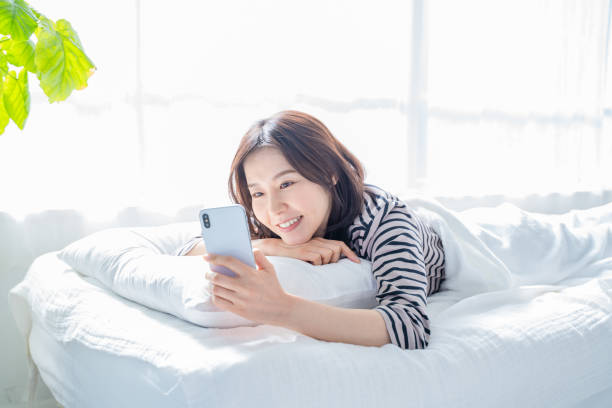 istock Smiling woman looking at smartphone screen in bed. 1452643322