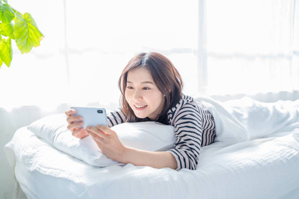 istock Smiling woman looking at smartphone screen in bed. 1452643338