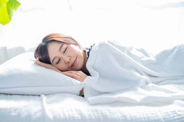 明るくシンプルな部屋のベッドで寝ている女性。