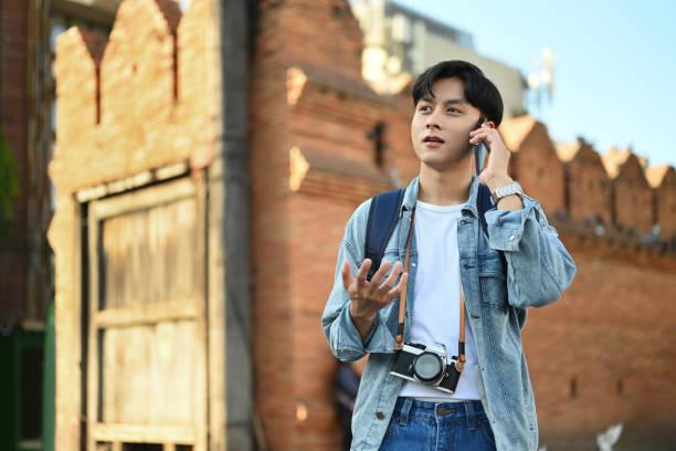 istock Young man talking on mobile phone while standing at Tha Phae Gate is a old city ancient wall in Chiang Mai northern Thailand. 1452646745