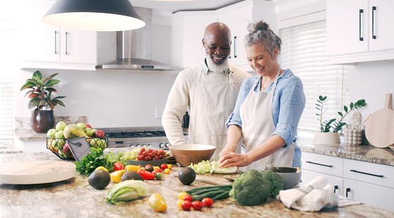 Nutrition, kitchen and cooking senior couple with vegetables, diet and health for breakfast. Food, wellness and interracial elderly man and woman with a smile for healthy lunch or dinner in a house