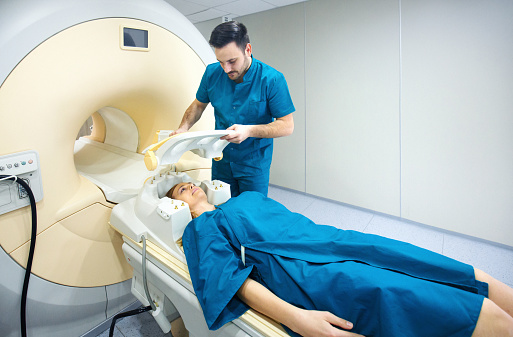 Closeup of a technician preparing a male patient for an MRI cranial scan.