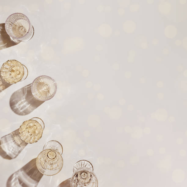 Summer party drinks flat lay, wine glasses with white sparkling wine and sunshine shadow on light table. Minimal pattern with beautiful wine glasses, above view still life, beige golden color Summer party drinks flat lay, wine glasses with white sparkling wine and sunshine shadow on light table. Minimal pattern with beautiful wine glasses, above view still life, beige golden neutral color champagne-glass-shadow stock pictures, royalty-free photos & images