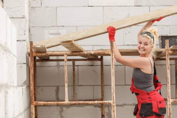 istock Woman carrying plank boards on construction site 1452651684