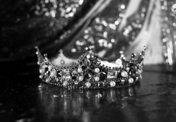istock Royal crown with precious gems on red luxury sparkle fabric background. Black and white. 1452651717