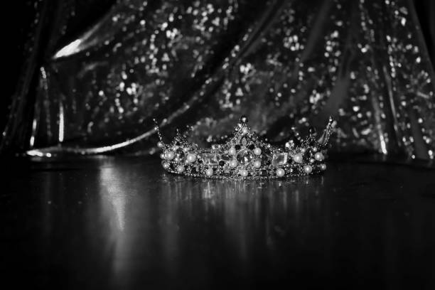 istock Royal crown with precious gems on red luxury sparkle fabric background. Black and white. 1452651729