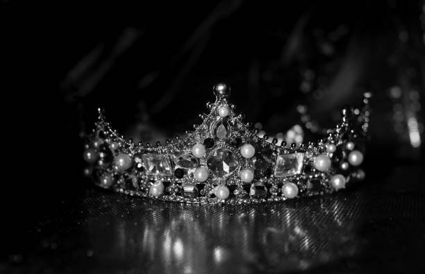 istock Magic crown with precious gems on red luxury sparkle fabric background. Black and white. 1452651737