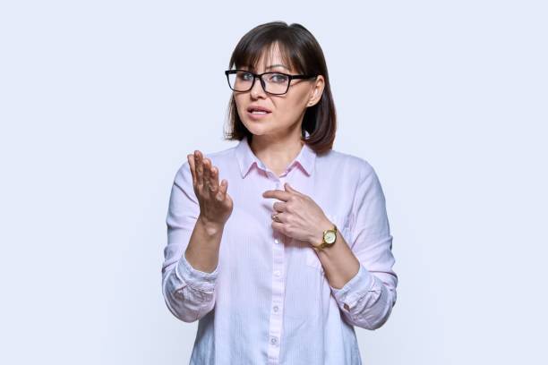 Talking gesturing woman looking at camera on light background stock photo