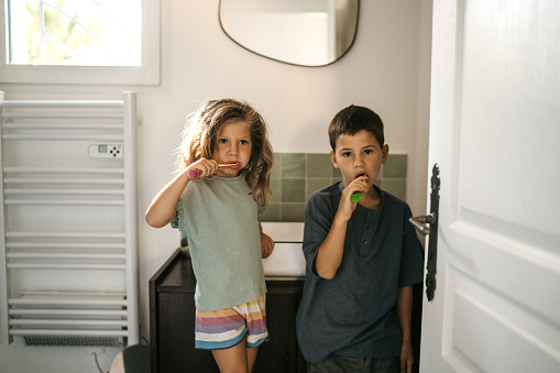 Little sister and brother brushing teeth together in the bathroom