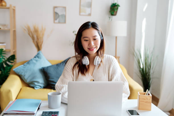 istock Smiling woman working on laptop at home 1452659912