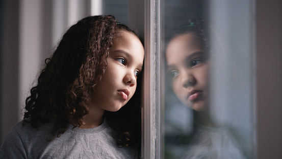 Mental health, girl and window for sad, thinking and depressed in home. Depression, black child and unhappy with stress, anxiety and frustrated with suffering, disappointed and foster female kid.