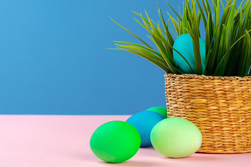 Colored eggs for Easter with pot of artificial grass. Creative photo