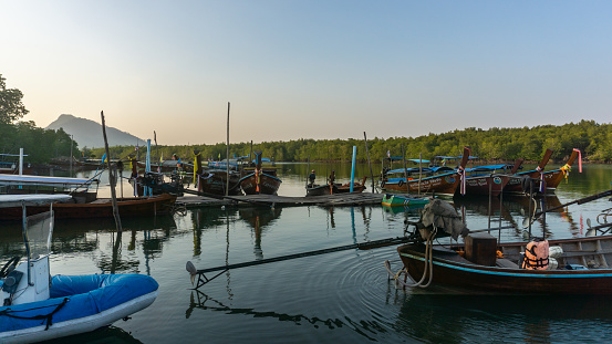 Colorful scenery of a local pier with beautiful and world-famous long-tail boats anchored in the pier, wooden, traditional hand made, decorated boats for transport.