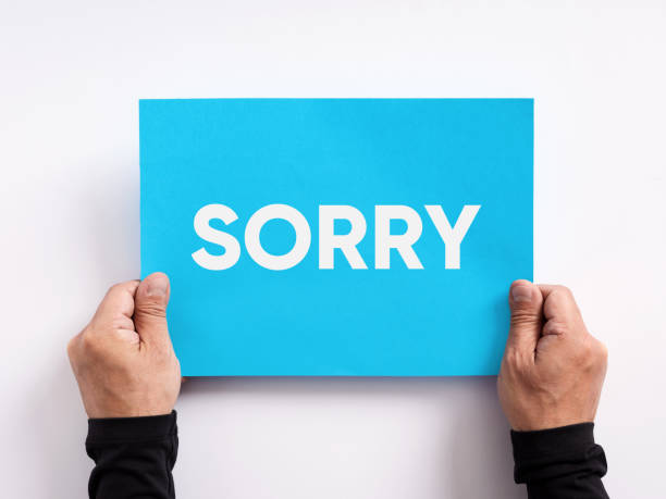 istock Male hand holding a blue paper with the message sorry. 1452662572