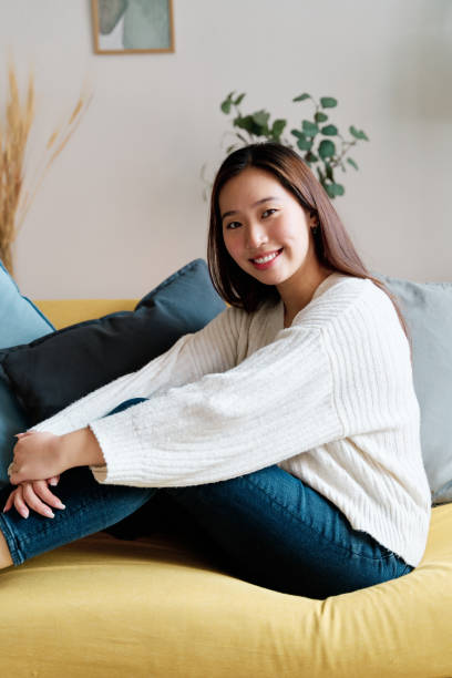 istock Smiling woman sitting on sofa 1452663379
