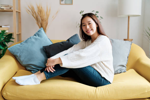istock Smiling woman sitting on sofa 1452663483
