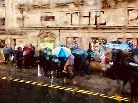 People queuing for the The Pavilion theatre in the rain with umbrellas on Boxing Day 2022 in Glasgow City centre