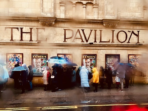 People queuing for the The Pavilion theatre in the rain with umbrellas on Boxing Day 2022 in Glasgow City centre