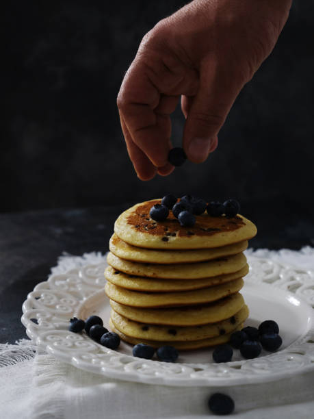 istock Man hand putting blueberries on pancakes 1452665435