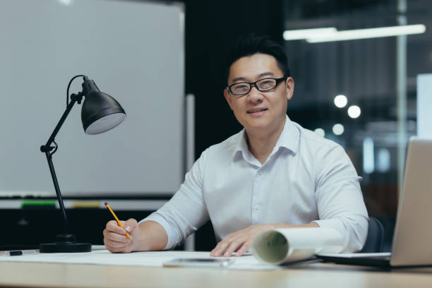 istock An Asian man, architect, designer, freelancer. Sitting in the office. Makes a drawing, makes a plan 1452667920