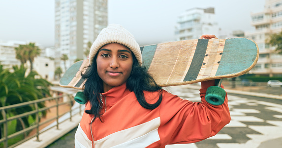 Indian woman, skater and skateboard happy, portrait smile and confident to practice for health and fun. Young hipster, gen z girl and ready to skate with board for outdoor training or relax in miami