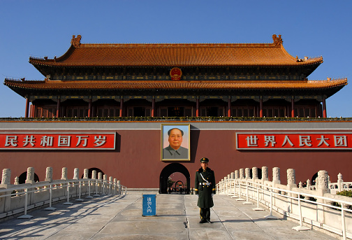 Guard standing in Tiananmen Square in front of the Gate of Heavenly Peace (Tian An Men) with a portrait of Mao Zedong (Mao Tse-tung or Chairman Mao). Tiananmen Square, Beijing, China.