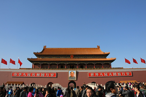 People in front of the Gate of Heavenly Peace (Tian An Men) in Tiananmen Square, Beijing, China. Tiananmen Square is a Beijing landmark visited by many tourists.