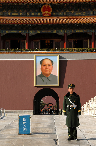 Guard standing in Tiananmen Square in front of the Gate of Heavenly Peace (Tian An Men) with a portrait of Mao Zedong (Mao Tse-tung or Chairman Mao). Tiananmen Square, Beijing, China.