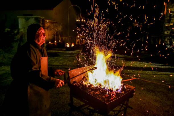 A blacksmith in medieval clothes in a representation of the Nativity of Christ in a small town in Umbria in Italy Gualdo Tadino, Umbria, Italy, December 26 -- A beautiful living scene of the Nativity of Christ made in period costumes by the people of the medieval village of Gualdo Tadino in Umbria, central Italy. In the image: An elderly blacksmith works iron between one of the scenes from the Nativity of Christ. An important center since Roman times, Gualdo Tadino rises between Foligno and Gubbio along the ancient Flaminia consular road, traced by the Romans. Its history spans the entire Middle Ages and, despite being partially destroyed and sacked several times and placed under the dominion of Perugia, this ancient Umbrian center still retains its medieval charm and traditions. The Umbria region, considered the green lung of Italy for its wooded mountains, is characterized by a perfect integration between nature and the presence of man, in a context of environmental sustainability and healthy life. In addition to its immense artistic and historical heritage, Umbria is famous for its food and wine production and for the high quality of the olive oil produced in these lands. Image in high definition format. gualdo tadino stock pictures, royalty-free photos & images
