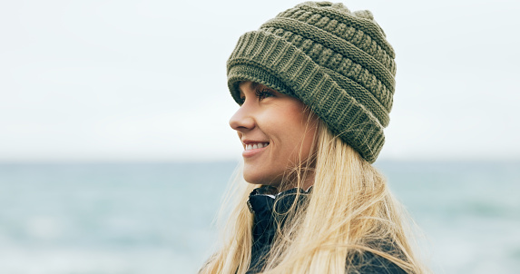 Wellness, happy and woman profile at beach with smile for travel, holiday and freedom. Happiness, ocean and peace of young girl with winter beanie in Australia enjoying vacation break.