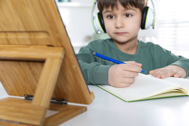 istock Cute little boy with tablet studying online at home, focus on hand. E-learning 1452670995