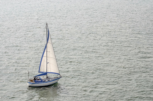 Crew member checking Genoa sail on sailboat.