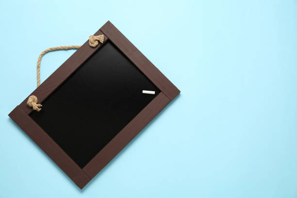 istock Clean small blackboard with piece of white chalk on light blue background, top view. Space for text 1452674279