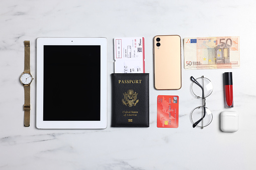Flat lay composition with documents, money and accessories on white marble background. Packing for business trip
