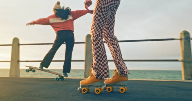 verão, diversão e amigos skate e patins juntos à beira-mar em férias, férias e fim de semana. liberdade, moda e meninas gostam de patinação, hobby de lazer e esporte de recreação para a aventura - skateboard park extreme sports recreational pursuit skateboarding - fotografias e filmes do acervo