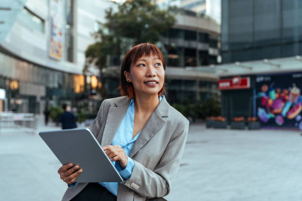 istock Young leading businesswoman using a wireless tablet while looking up outdoors. 1452677805