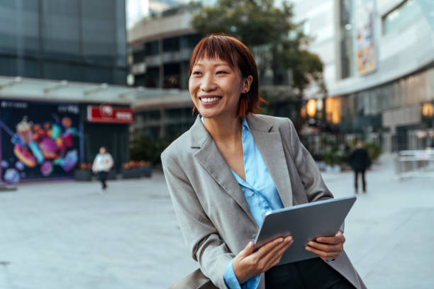 istock Attractive businesswoman using a digital tablet while standing on the street. 1452677827
