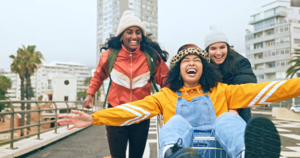 girl friends, shopping cart and fun of women in winter feeling freedom and happiness from travel. cart race, running and happy friend group with a smile and free feeling outdoor in los angeles - friendship women group of people 20s imagens e fotografias de stock