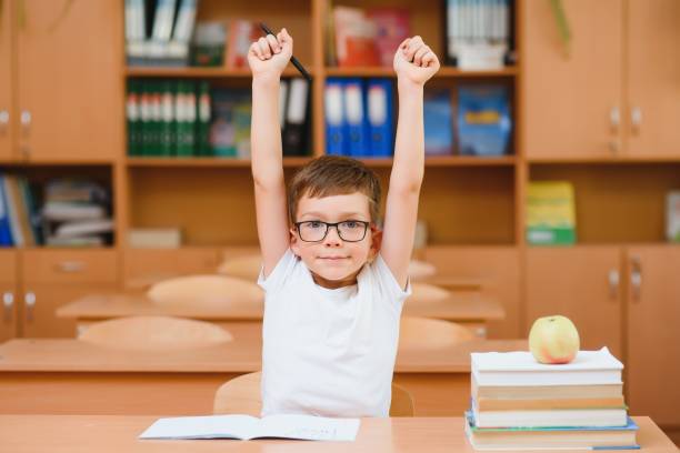 istock Happy schoolboys sitting at desk, classroom 1452678100