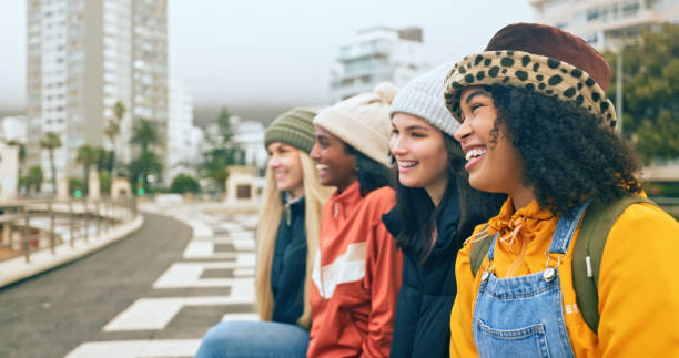 都市の幸せな女性、友人、冬のファッション、都会のライフスタイル、ダウンタウンの若者文化、z世代の態度と幸福。寒い季節に屋外でたむろする若い女の子、多様性、女性グループ - multi ethnic group outdoors 20s student ストックフォトと画像