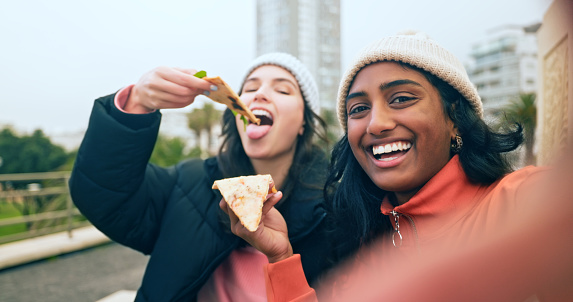 Women, pizza selfie and friends in city, having fun and eating outdoors. Face, food and girls taking photo for happy memory, social media profile picture or internet post while enjoying time together