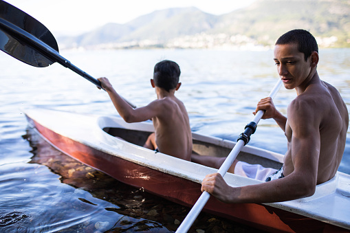 Two boys are having fun paddling a kayak at the seaside