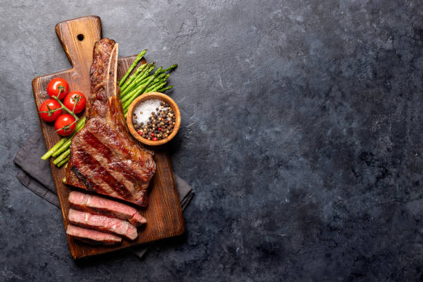 bistecca di manzo tomahawk alla griglia mediamente rara con asparagi - steak plate gourmet beef foto e immagini stock