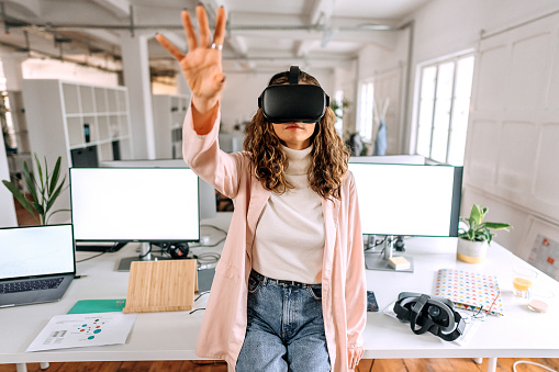 Young beautiful woman using VR goggles in the modern office