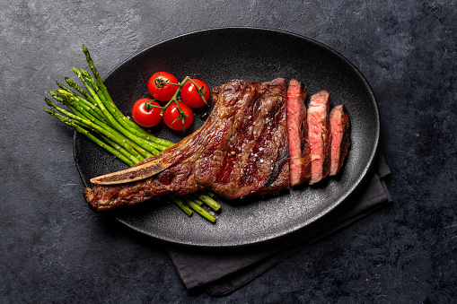 Medium rare grilled Tomahawk beef steak with asparagus. Flat lay