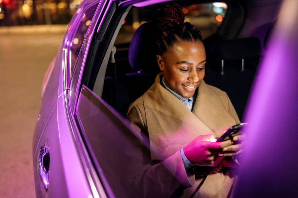 donna d'affari ben vestita messaggi di testo dal sedile posteriore di un'auto - taxi travel business women foto e immagini stock