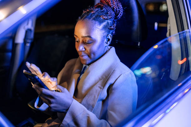 istock Well dressed young businesswoman text messaging from hes car 1452686400