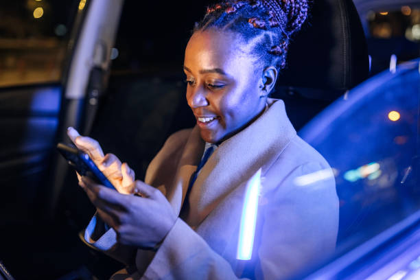 istock Well dressed young businesswoman text messaging from hes car 1452686404