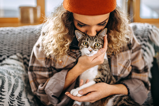 Close up shot of young woman bonding with her cat in apartment